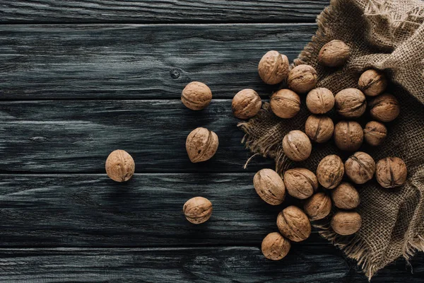 Noix en coquilles de noix avec sac sur une surface en bois sombre — Photo de stock