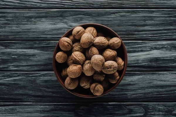 Walnuts in wooden bowl on dark wooden background — Stock Photo