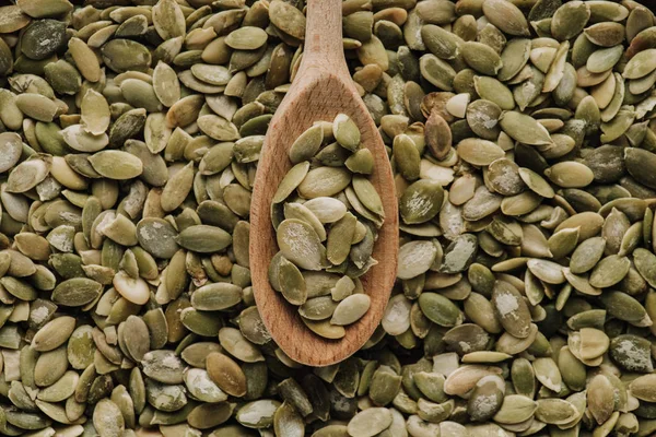 Top view of pumpkin seeds and wooden spoon — Stock Photo