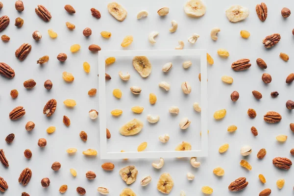 Top view of white frame on dried fruits and nuts isolated on white background — Stock Photo