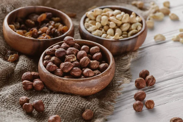 Assorted nuts in wooden bowls on sackcloth — Stock Photo