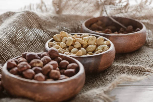 Mezcla de frutos secos en cuencos de madera sobre tela de saco - foto de stock