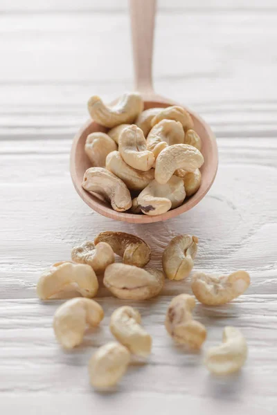 Cashew in wooden spoon on white wooden tabletop — Stock Photo