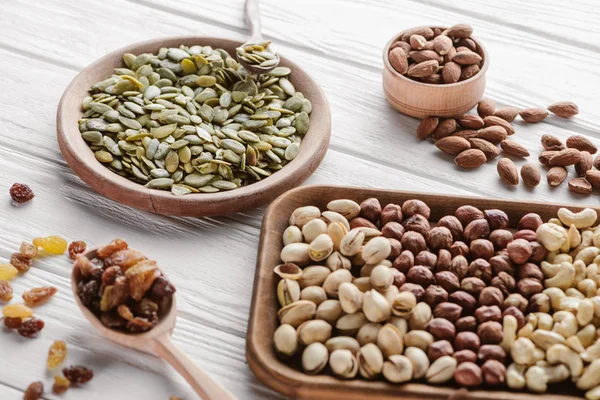 Assorted delicious nuts and raisins in wooden plates and spoon — Stock Photo