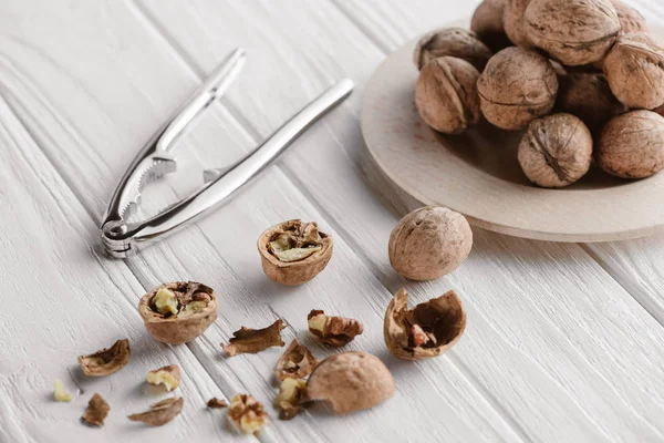 Коричневые грецкие орехи с металлическим крекером на деревянном столе — стоковое фото