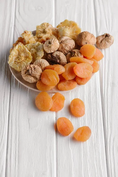 Variety of dried fruits on white plate on wooden surface — Stock Photo