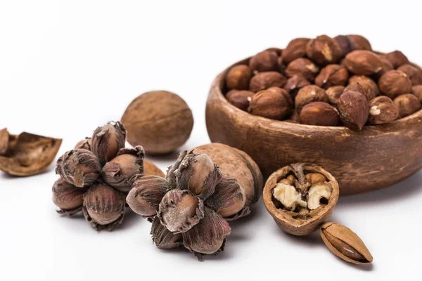 Hazelnuts in wooden bowl near walnuts and almond isolated on white background — Stock Photo