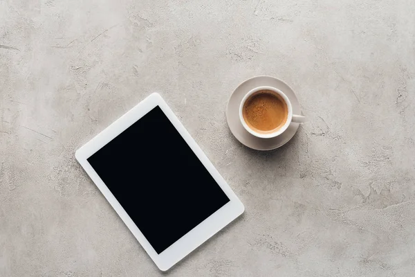 Vue du dessus de la tasse de café et de la tablette avec écran blanc sur la surface en béton — Photo de stock