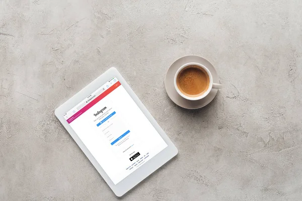 Draufsicht auf Tasse Kaffee und Tablet mit instagram-Website auf dem Bildschirm auf Betonoberfläche — Stockfoto