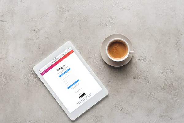 Vista superior da xícara de café e tablet com site instagram na tela na superfície de concreto — Fotografia de Stock