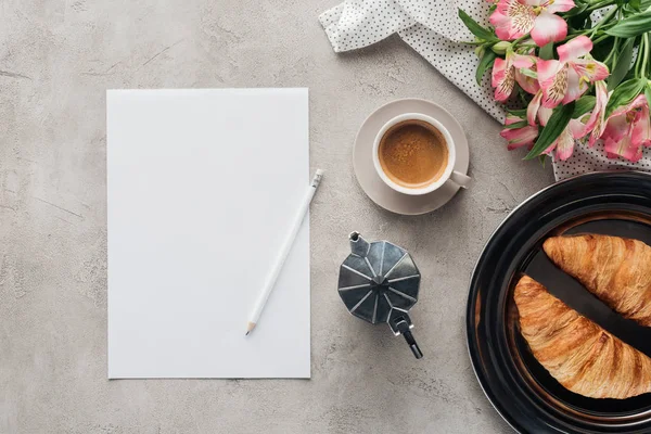 Top view of cup of coffee with blank paper, croissants and alstroemeria bouquet on concrete surface — Stock Photo