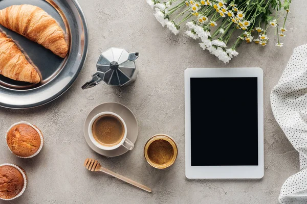 Вид сверху на кофе с кондитерскими изделиями и планшетами с чистым экраном на бетонной поверхности — стоковое фото