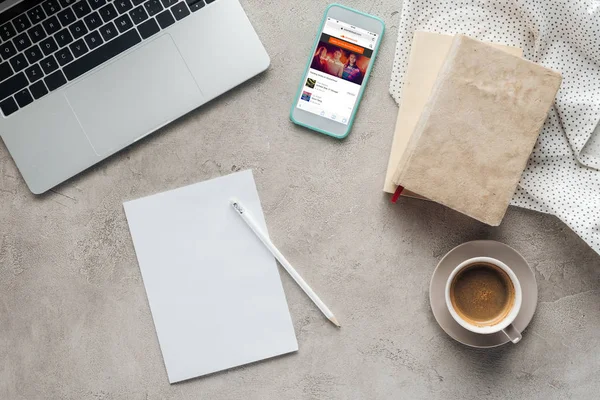 Top view of coffee with laptop and smartphone with soundcloud app on screen on concrete surface with blank paper — Stock Photo