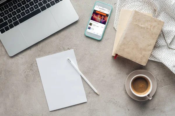 Vue du haut du café avec ordinateur portable et smartphone avec application soundcloud à l'écran sur une surface en béton avec papier vierge — Photo de stock