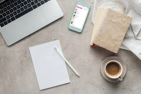 Vue de dessus du café avec ordinateur portable et smartphone avec application de lecteur de musique à l'écran sur la surface en béton avec papier blanc — Photo de stock