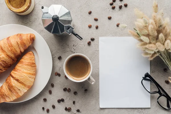 Vue de dessus de tasse de café avec des croissants et du papier blanc sur la surface du béton — Photo de stock