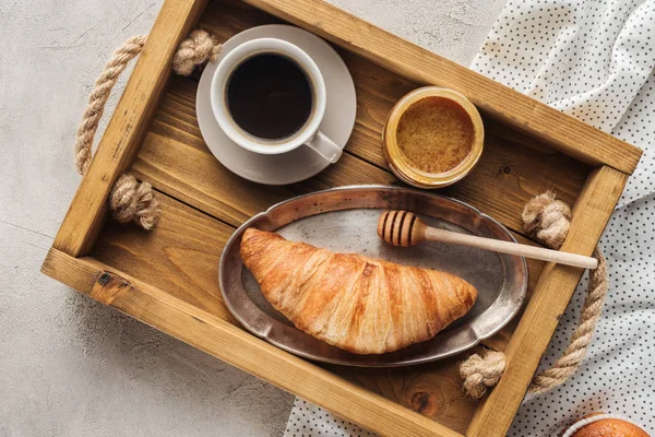 Vue de dessus de tasse de café avec croissant et miel sur plateau sur la surface du béton — Photo de stock