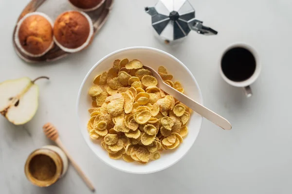 Top view of bowl of dry cereal with delicious coffee and muffins on white — Stock Photo