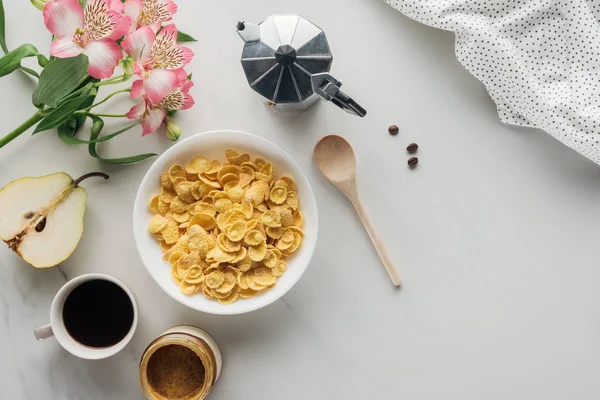 Draufsicht auf Schüssel mit trockenem Müsli mit Kaffee und Alstroemeria-Bouquet auf weißem Grund — Stockfoto