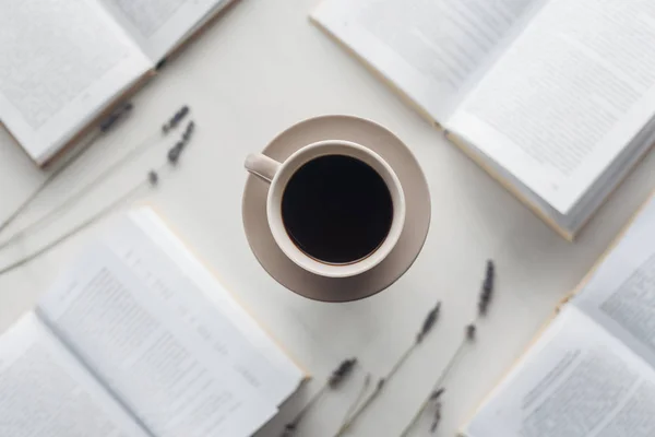 Top view of cup of delicious coffee surrounded with books and field flowers on white — Stock Photo