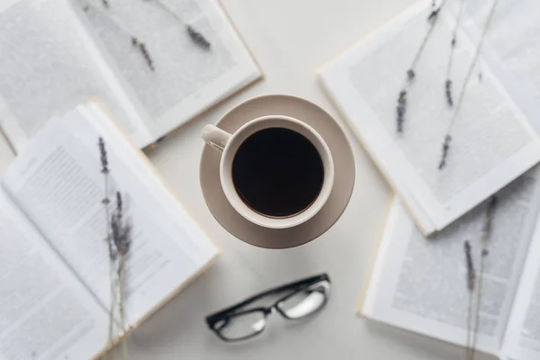 Draufsicht auf Tasse Kaffee, umgeben von Büchern und Feldblumen auf weiß — Stockfoto