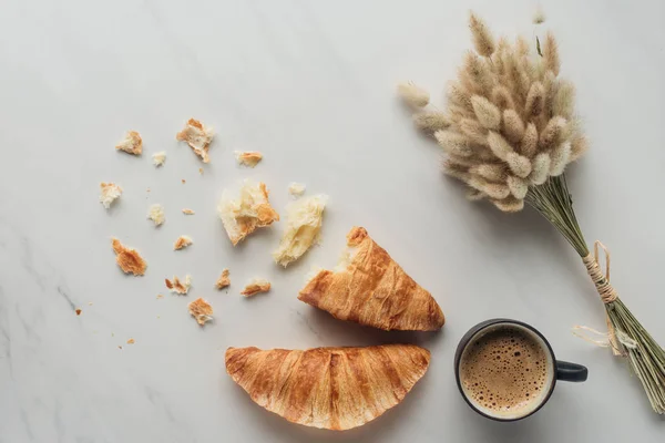 Draufsicht auf Tasse köstlichen Kaffee mit Croissants und Strauß Hasenschwanzohren auf weißem Marmor — Stockfoto