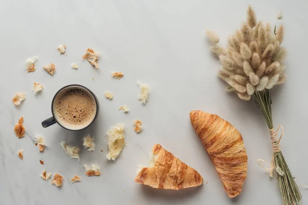 Vue de dessus de tasse de café avec croissants et bouquet d'oreilles de lapin sur marbre blanc — Photo de stock