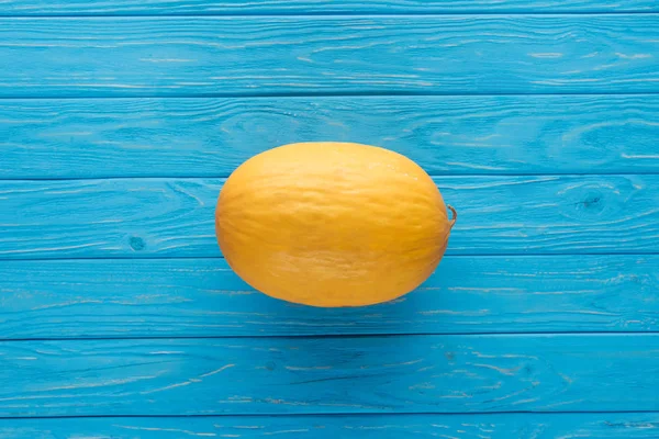 Top view of whole ripe yellow melon on blue wooden surface — Stock Photo