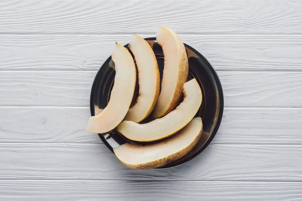 Vista dall'alto di deliziosa melone affettato melata sul piatto sulla superficie di legno — Foto stock