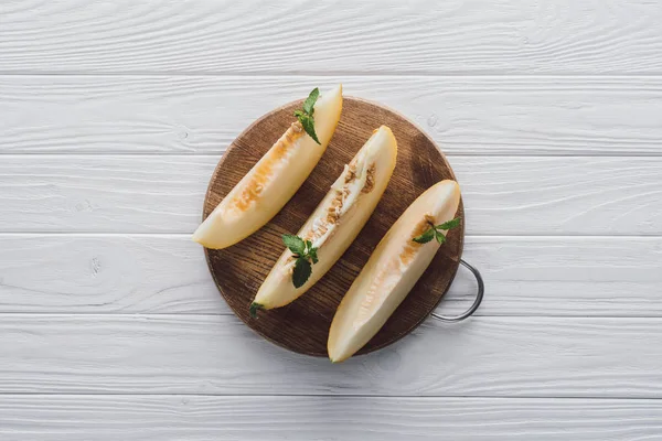 Top view of delicious honeydew melon with mint on wooden board — Stock Photo