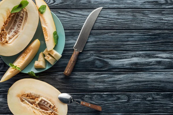 Vista superior de melão maduro doce com colher e faca na superfície de madeira — Fotografia de Stock