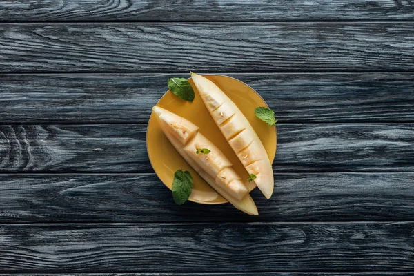 Draufsicht auf frische reife süße Melonenscheiben auf gelbem Teller auf Holzoberfläche — Stockfoto