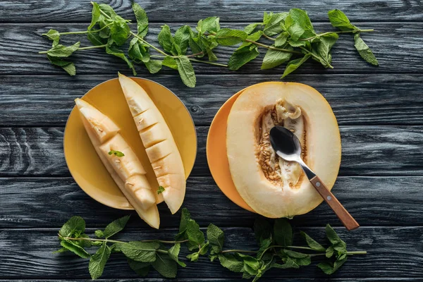 Draufsicht auf frische reife süße Melone mit Löffel und frischer Minze auf Holzoberfläche — Stockfoto