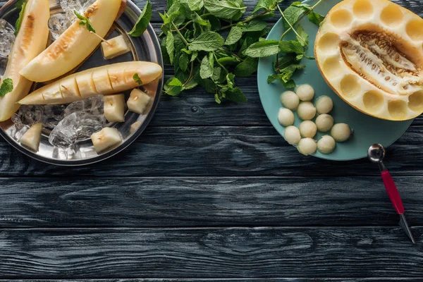 Vue de dessus du melon sucré mûr avec glaçons, menthe fraîche et boules de melon sur la surface en bois — Photo de stock