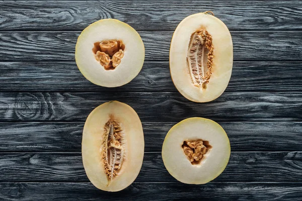Vue de dessus des melons mielleux et cantaloups mûrs coupés en deux sur la surface en bois — Photo de stock