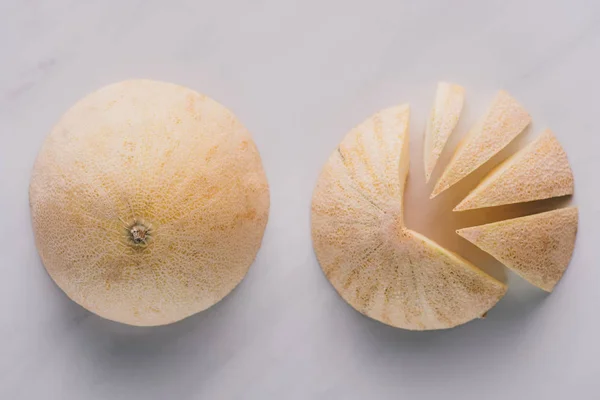 Vista superior de melones enteros y en rodajas de melón sobre blanco - foto de stock