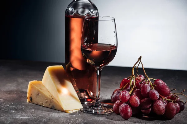 Botella de vino, copa, quesos y uvas en gris - foto de stock