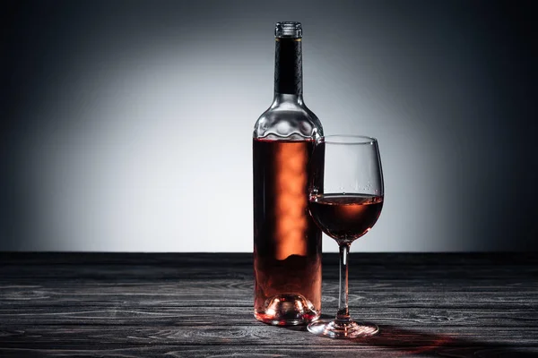 Botella de vino tinto y vino sobre mesa de madera - foto de stock
