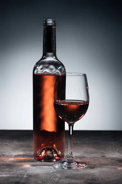 Пляшка червоного вина та келиха на сірому — стокове фото