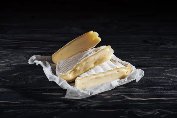 Кусочки вкусного сыра бри на деревянном столе — стоковое фото
