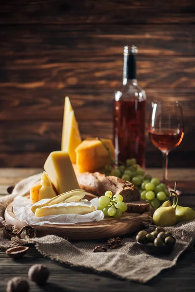Different types of cheeses, grapes and pears on wooden tabletop — Stock Photo