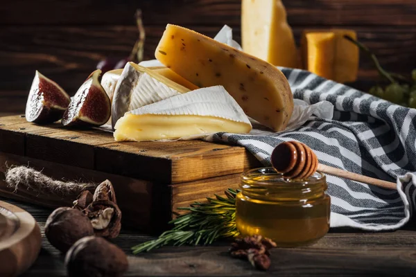 Diferentes tipos de quesos, miel, higo y nueces en la mesa - foto de stock