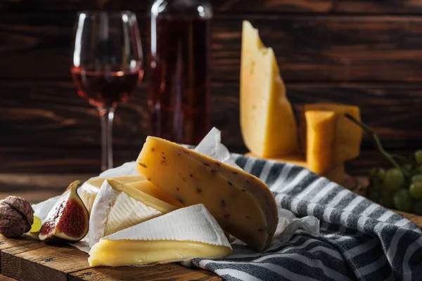 Diferentes tipos de queijos, figo e noz em tábua de madeira — Fotografia de Stock
