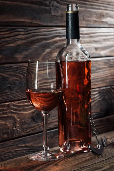 Bouteille de vin, verre de vin et tire-bouchon sur table en bois — Photo de stock
