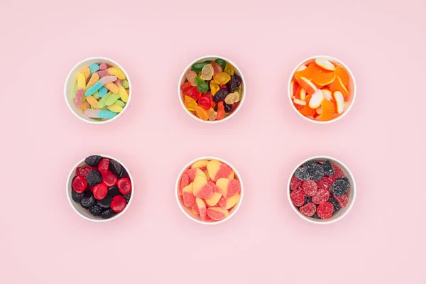Vue de dessus des tasses en papier avec bonbons gelée isolé sur rose — Photo de stock