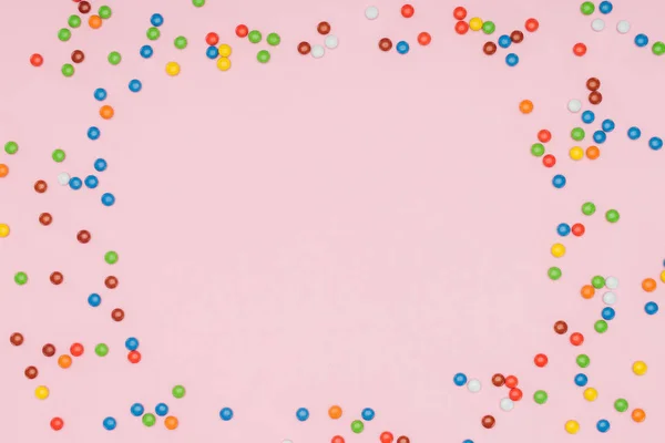 Vista superior de doces de dragee coloridos dispersos isolados em rosa — Fotografia de Stock