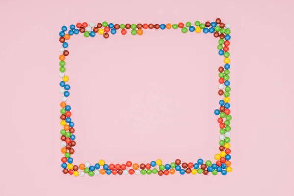 Top view of frame of dragee candies isolated on pink — Stock Photo