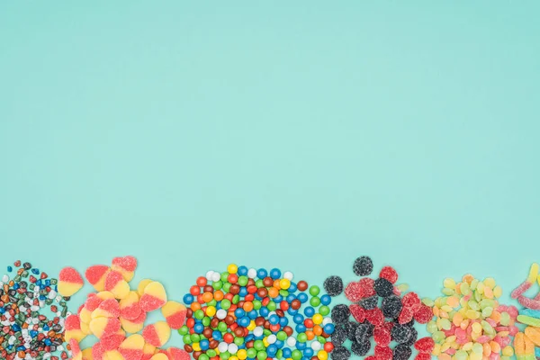 Vista superior de diferentes dulces de colores aislados en turquesa - foto de stock