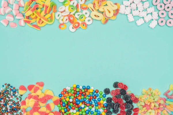 Vista superior de caramelos de gelatina, malvaviscos y dragee aislados en turquesa - foto de stock