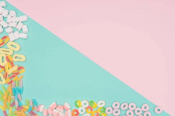 Top view of jelly candies and marshmallows on turquoise and pink surface — Stock Photo